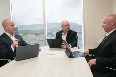 Three Amati partners discussing work around a boardroom table